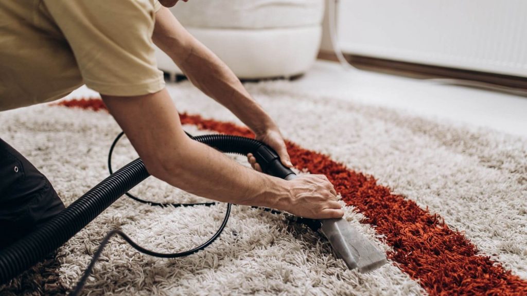 a picture of a man scrubbing clean a carpet